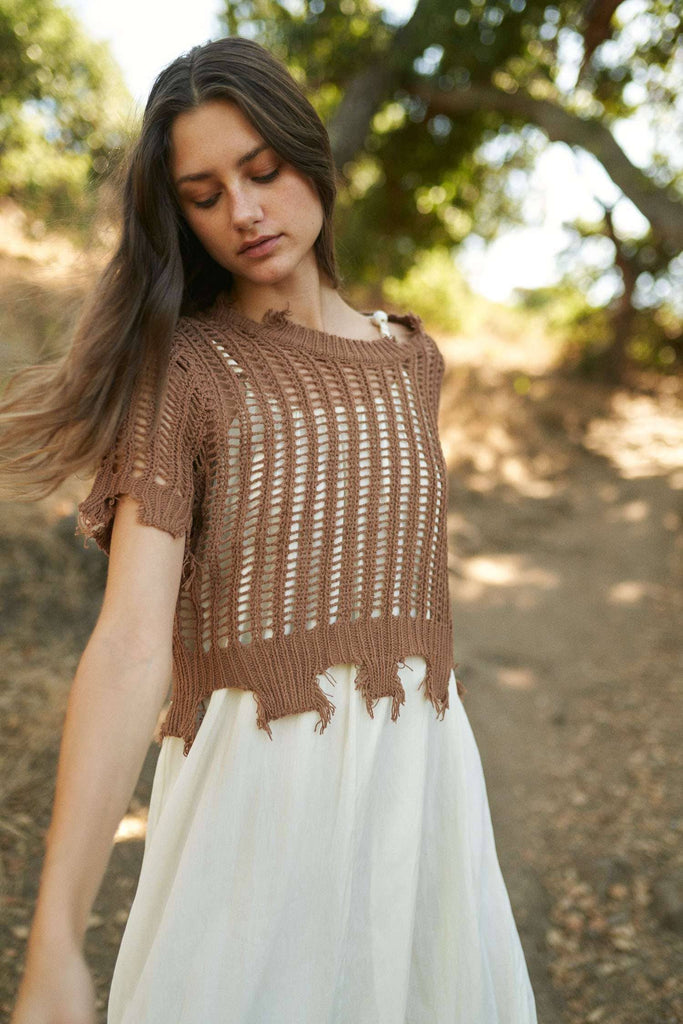 Woman wearing a brown knitted top and white skirt outdoors