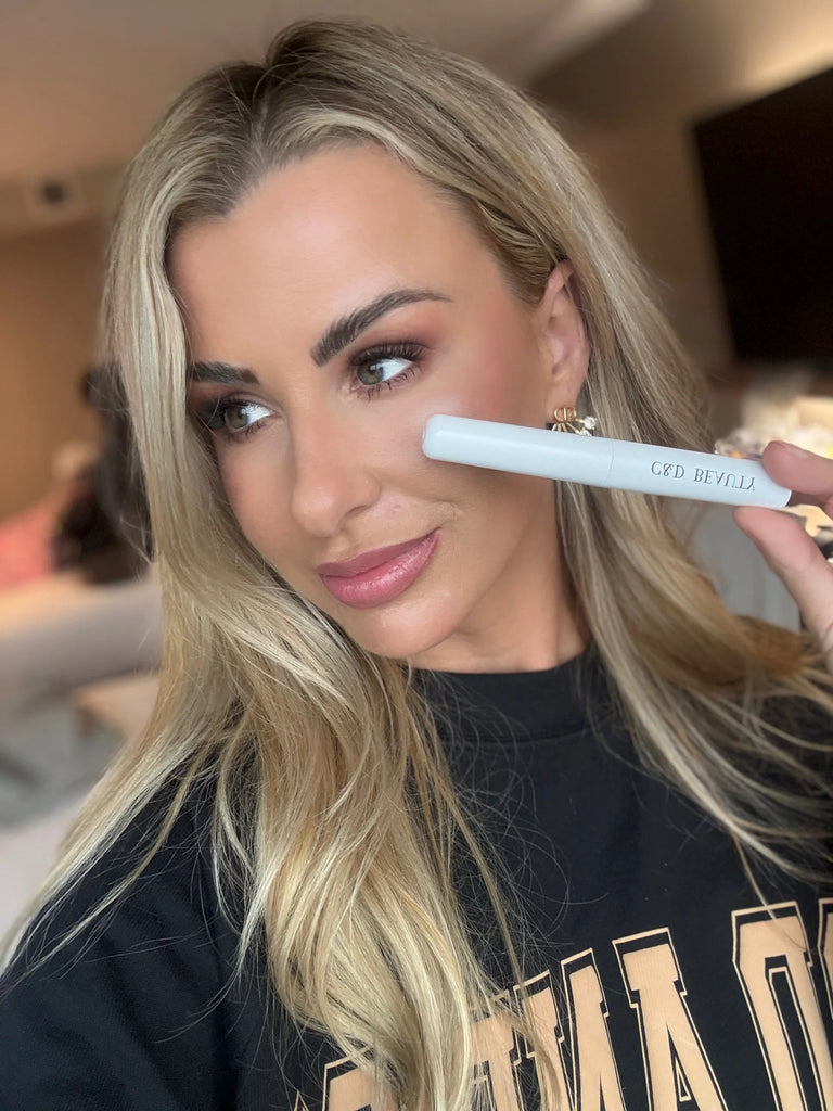 Woman holding a makeup product with a blurred background