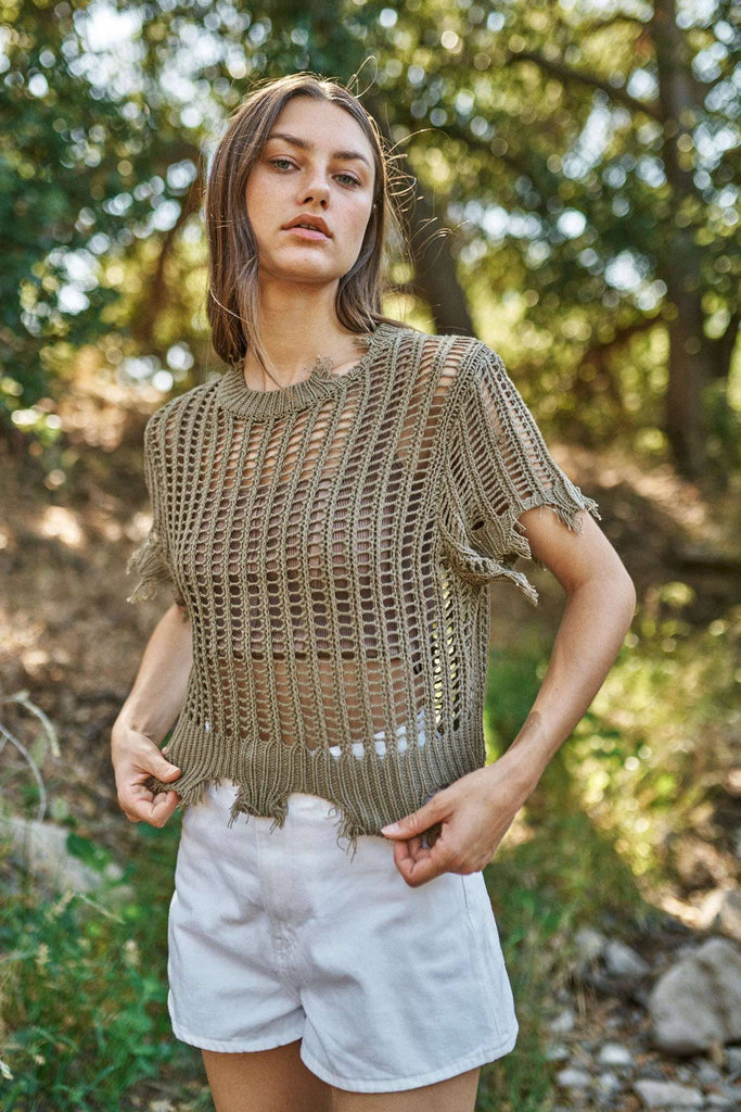 Woman wearing a crochet top and white shorts in a natural setting