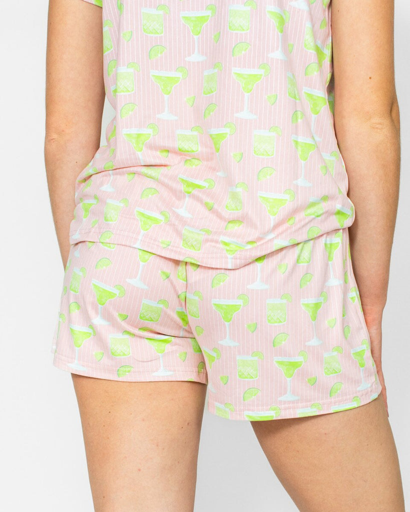 Pink shorts with green abstract patterns on a plain background