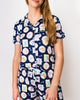 Woman wearing a navy blue pajama set with colorful dog-themed pattern on a white background