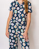 Person wearing a navy blue pajama set with colorful dog pattern on a plain background