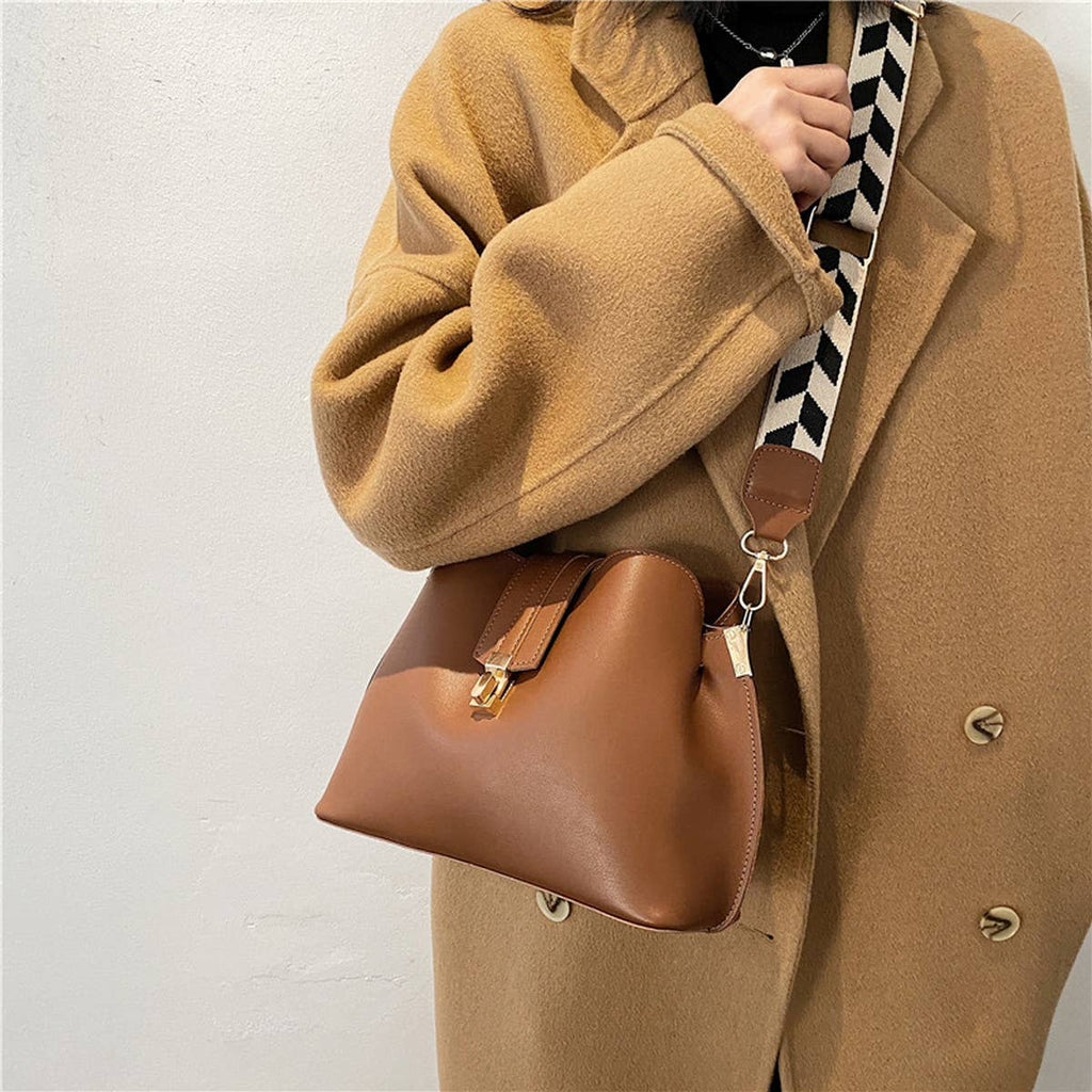 Person wearing a tan coat holding a brown handbag with a checkered strap.