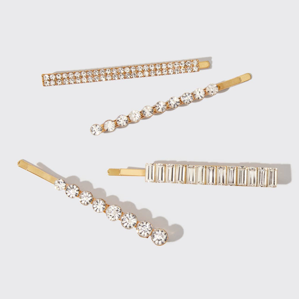 Set of four gold hair pins with crystal embellishments on a light gray background