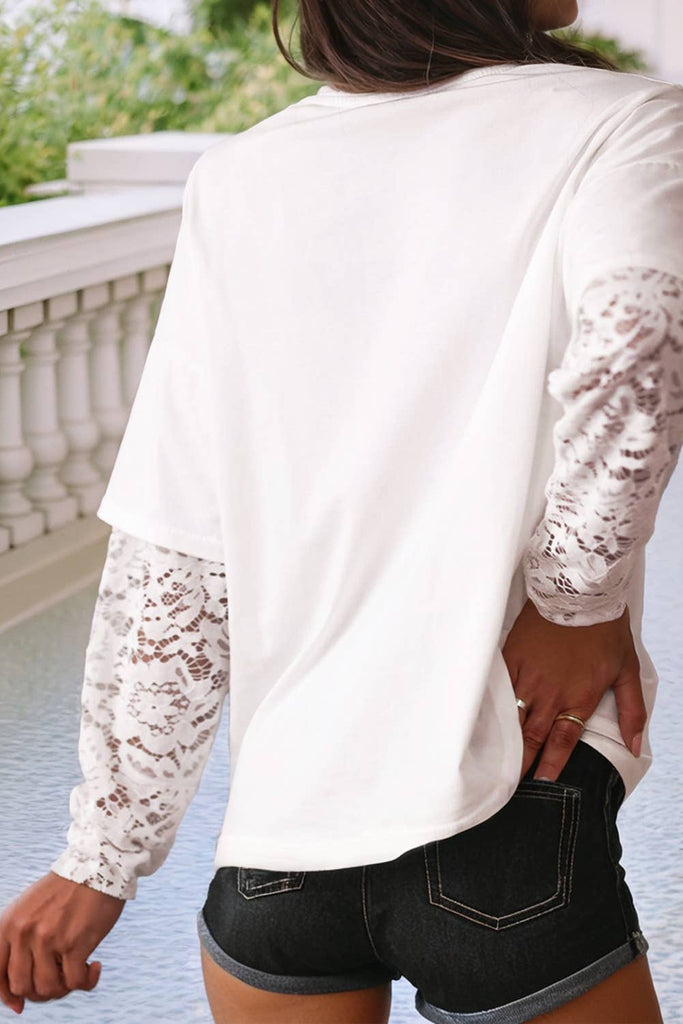 Person wearing a white lace-trimmed top and black shorts outdoors.