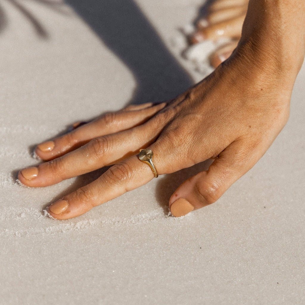 Hand with a gold ring on a sandy surface