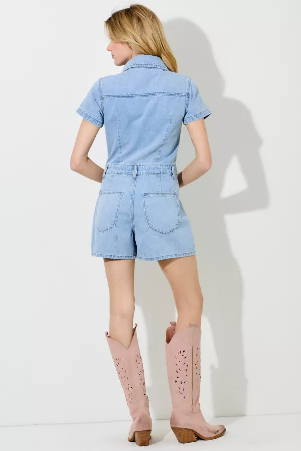 Woman wearing a light blue denim romper with pink knee-high boots on a white background