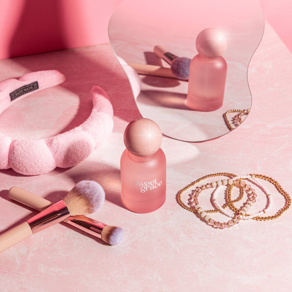 Pink makeup products and tools on a pink surface with 'sweet grace' branding.