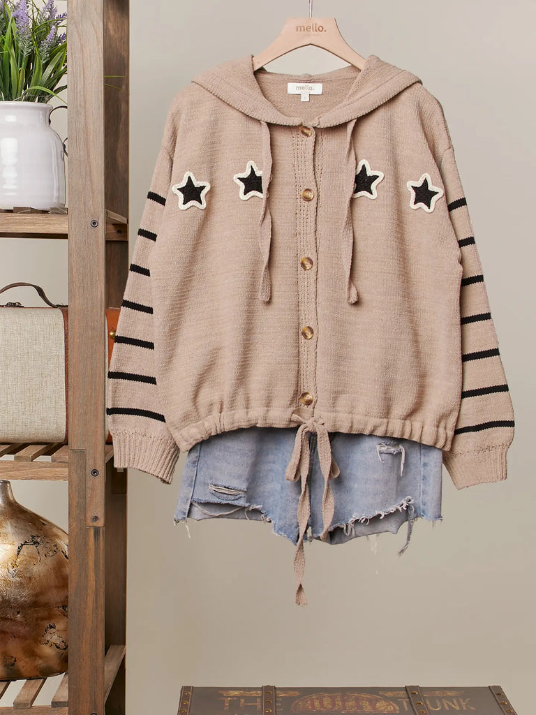 Taupe knit button-up hoodie with black star appliqués, striped sleeves, and drawstring hem, styled with a relaxed fit for casual boutique fashion.