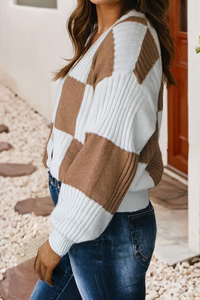 Person wearing a brown and white patterned sweater with blue jeans outdoors.