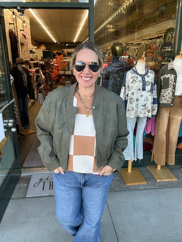Woman standing outside a store with mannequins and clothing in the background