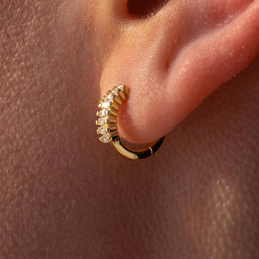 Gold hoop earring with small diamonds on a person's ear