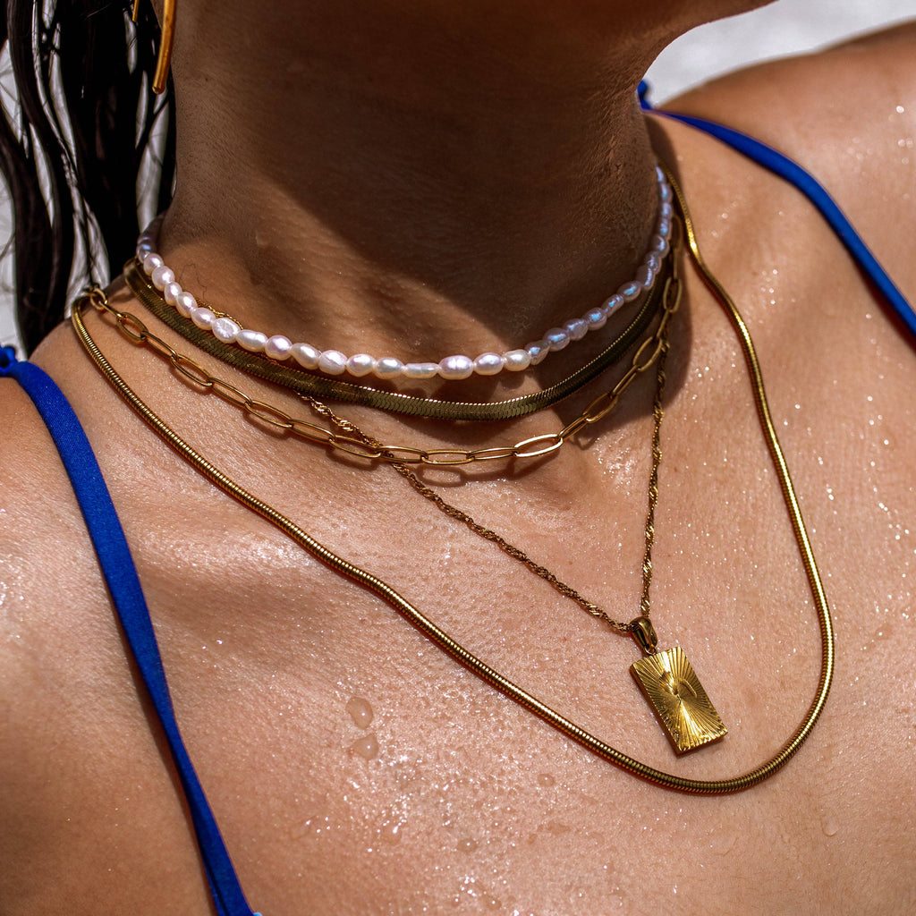 Close-up of a person wearing multiple necklaces with a focus on gold chains.