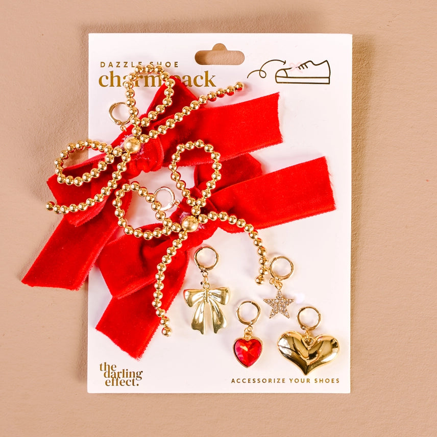 Shoe charm pack with red ribbons and gold charms on a beige background