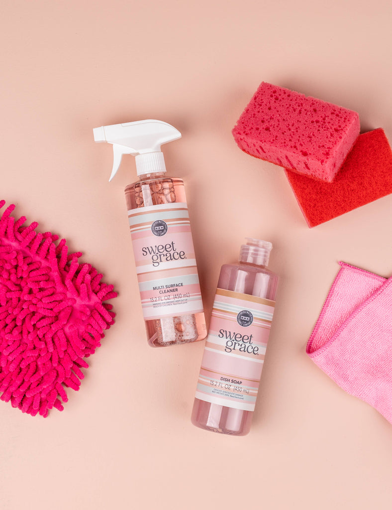 Two bottles of 'Sweet Grace' cleaning products with cleaning tools on a beige background