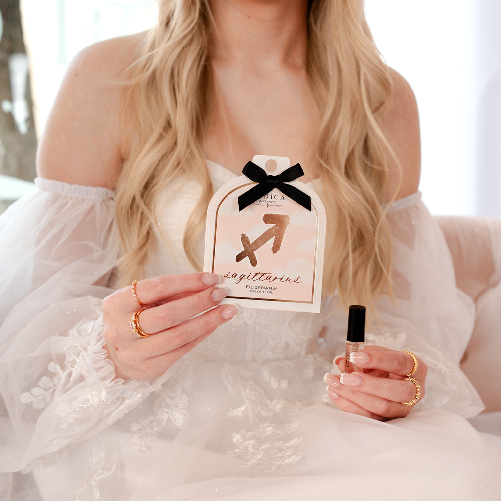 Person holding a perfume bottle and its packaging with a zodiac symbol