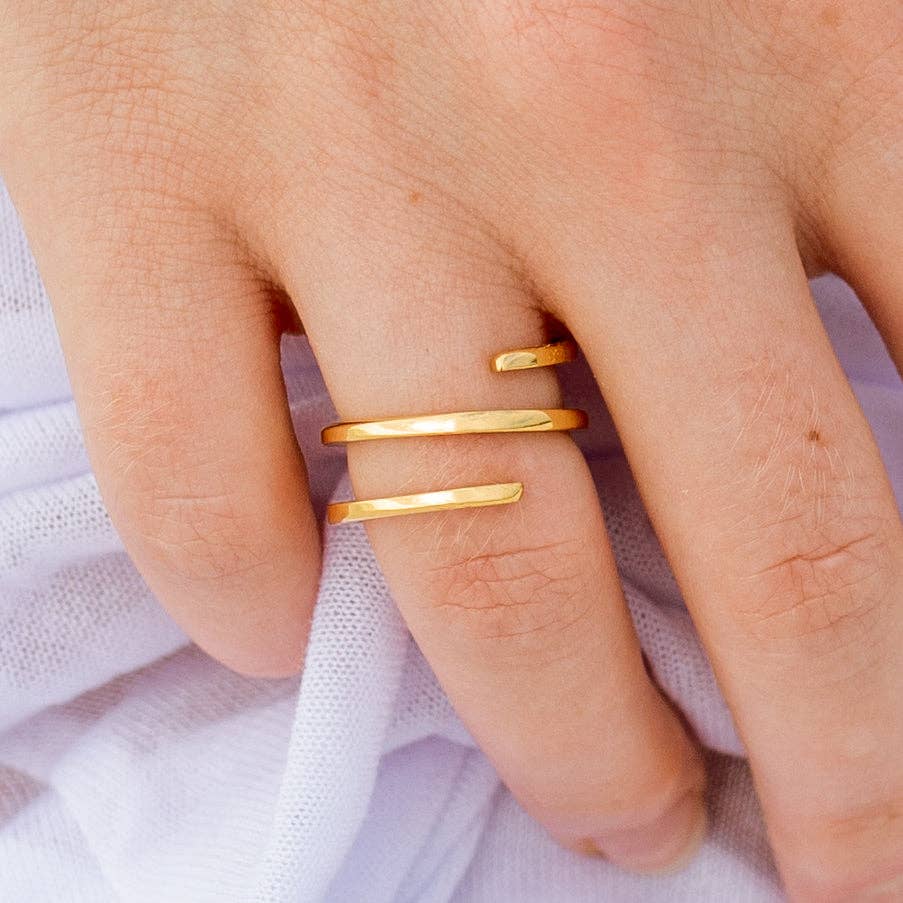 Gold rings on a person's finger against a light purple fabric background
