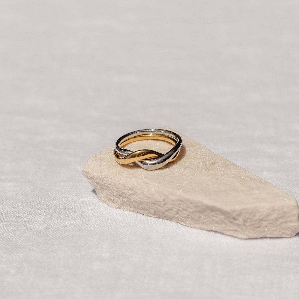 Two gold rings stacked on a light stone surface