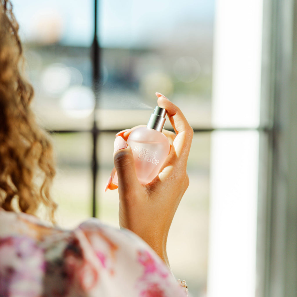 Person holding a pink perfume bottle with a blurred background