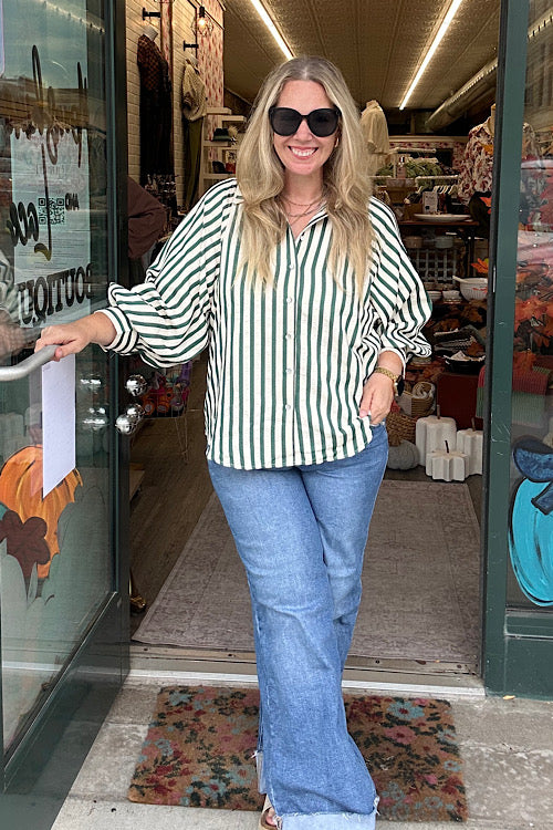 Woman wearing Eliza hunter green and cream vertical stripe button down top with relaxed fit and cuff detail, styled with denim jeans.