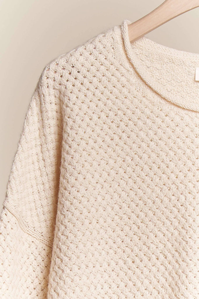 Close-up of a textured beige sweater on a neutral background