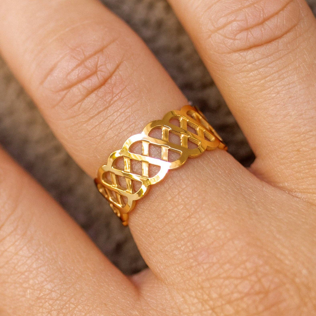 Gold ring with intricate design on a finger