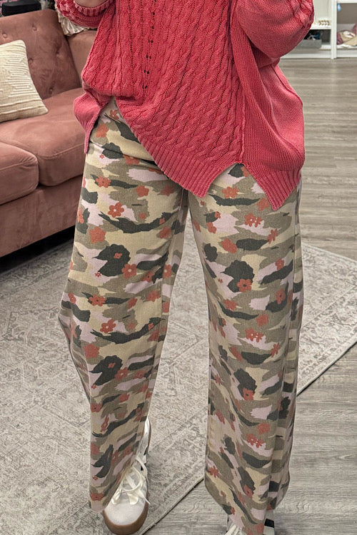 Person wearing a pink sweater and camouflage pants in a living room setting.