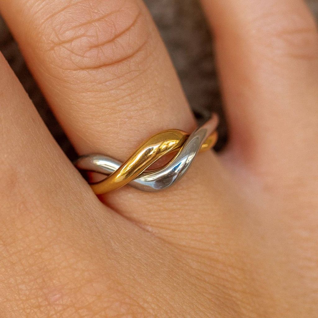 Gold and silver ring on a finger with a blurred background