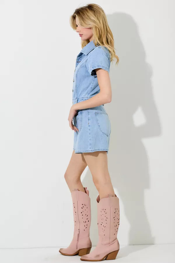 Woman wearing a light blue denim dress and pink cowboy boots against a white background