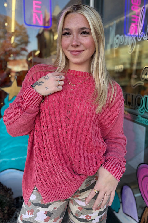 Woman wearing a pink sweater in front of a colorful store window