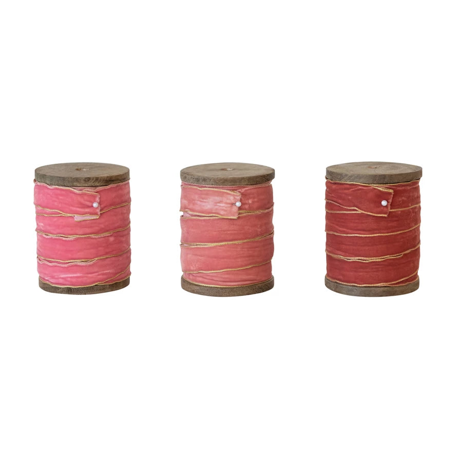 Set of three velvet ribbons with metallic edges on wood spools in blush, baby pink, and rust tones, each sold individually.