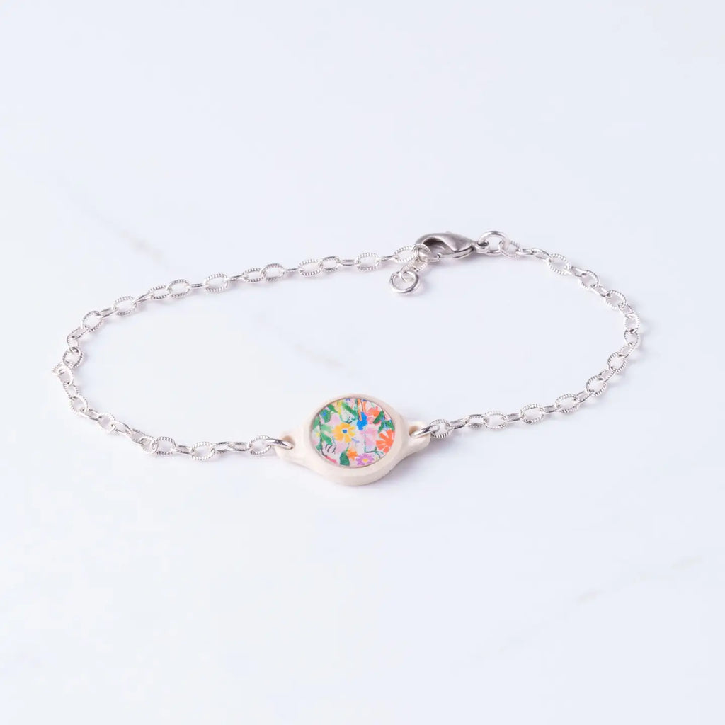 Silver bracelet with a floral charm on a white background