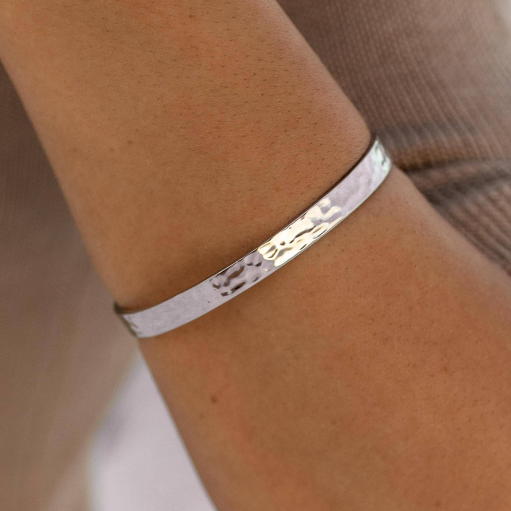 Silver bracelet on a wrist with a neutral background