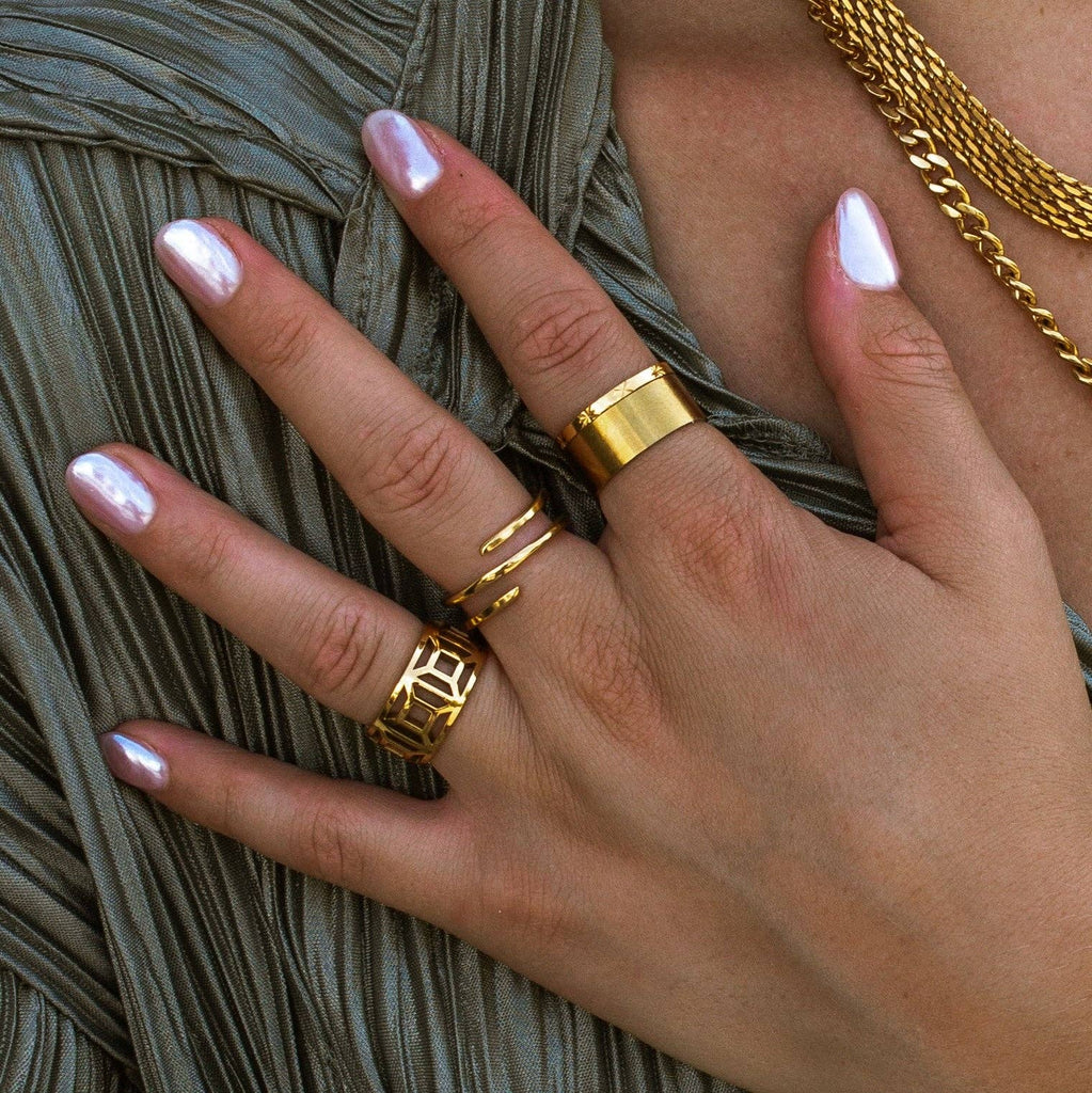 Hand wearing gold rings with a neutral background