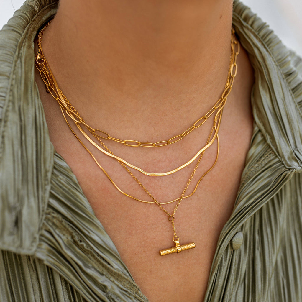 Close-up of a person wearing multiple gold necklaces with a green top.