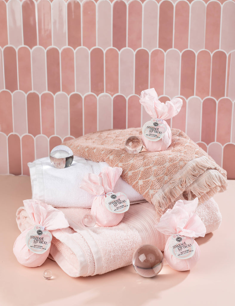 Pink bath products with towels on a pink tiled background