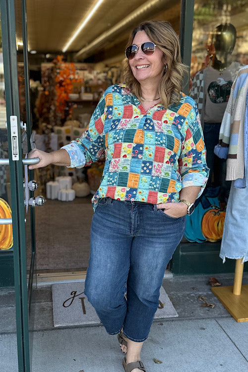 Person wearing a patchwork quilt jacket with floral and geometric patterns.