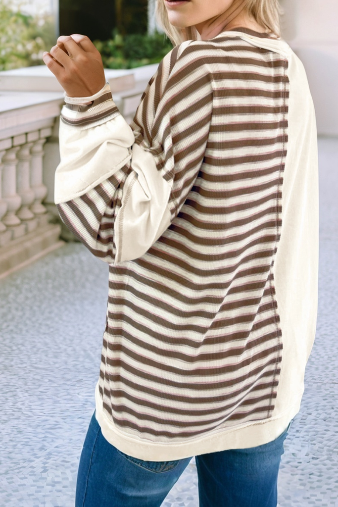Person wearing a brown and beige striped long-sleeve top with a blurred background