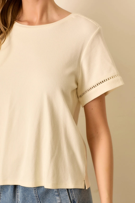 Beige short-sleeve top with decorative trim on a beige background