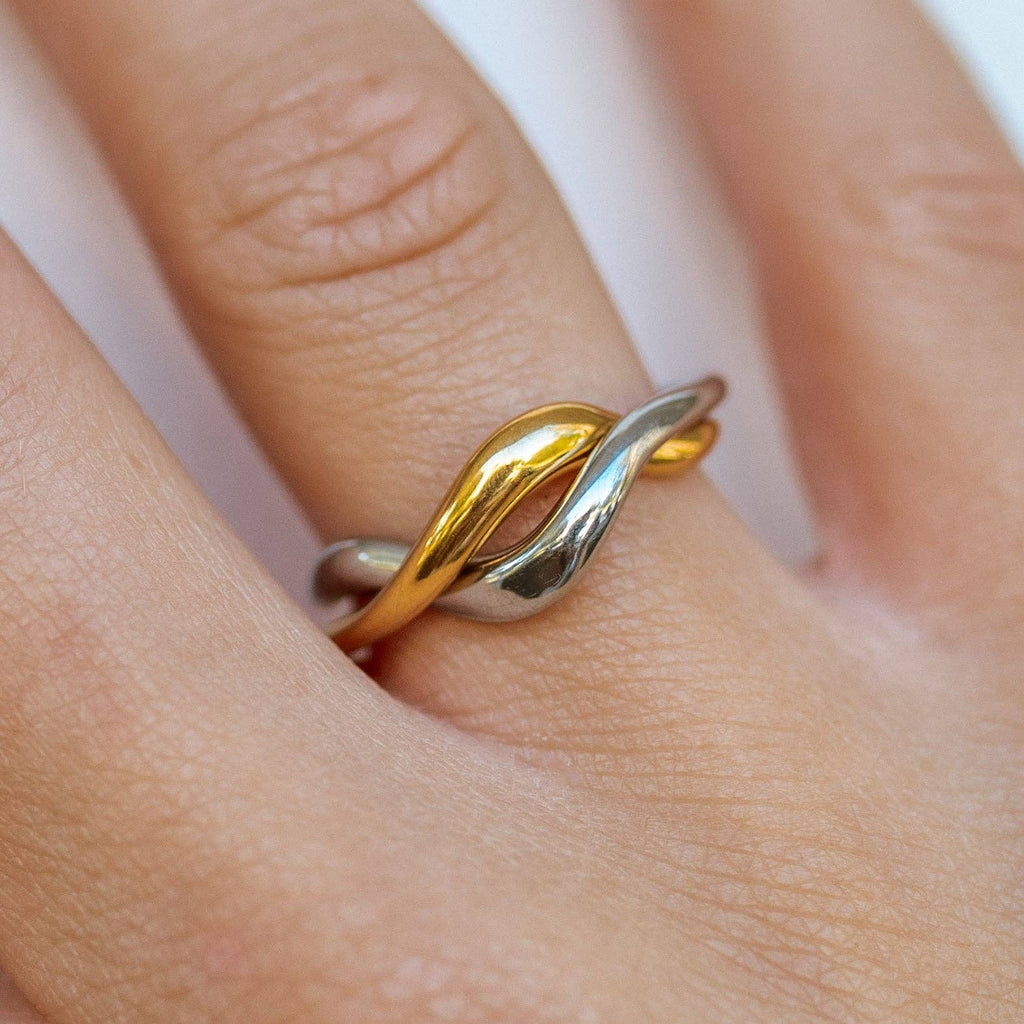 Gold and silver ring on a finger with a white background