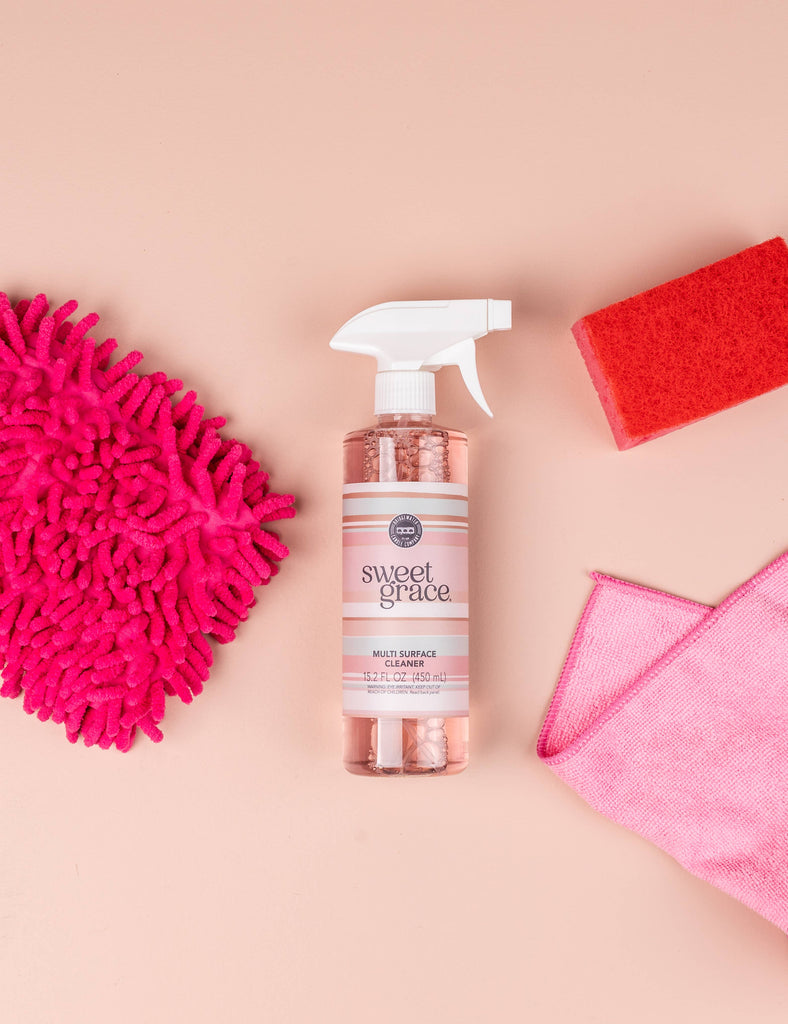 Bottle of 'sweet grace' surface cleaner with cleaning tools on a beige background