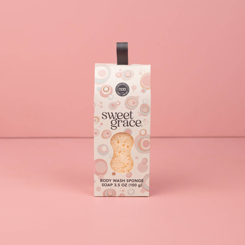 Box of 'sweet grace' body wash sponge on a pink background