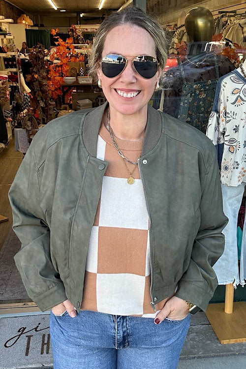 Woman wearing sunglasses and a green jacket in a store setting