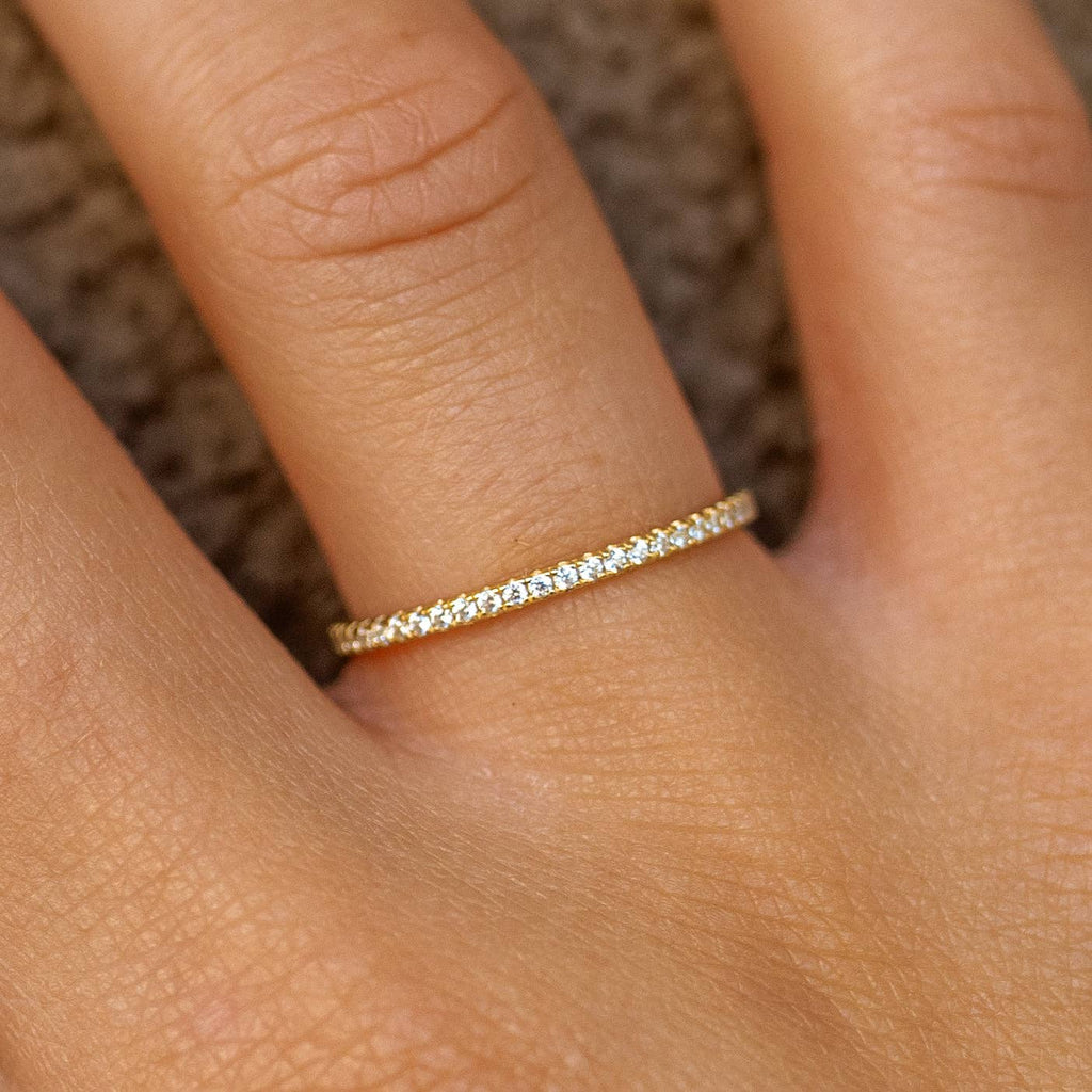 A gold-plated, sterling silver ring with cubic zirconia embellishments, worn on a person's finger.