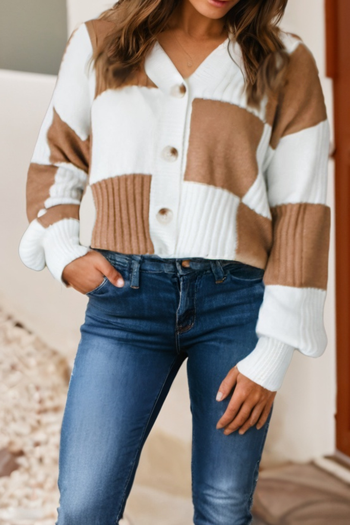 Person wearing a brown and white checkered cardigan with blue jeans.