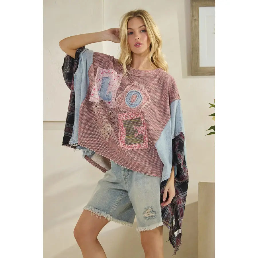 Woman wearing a colorful, patchwork sweater with text and patterns.