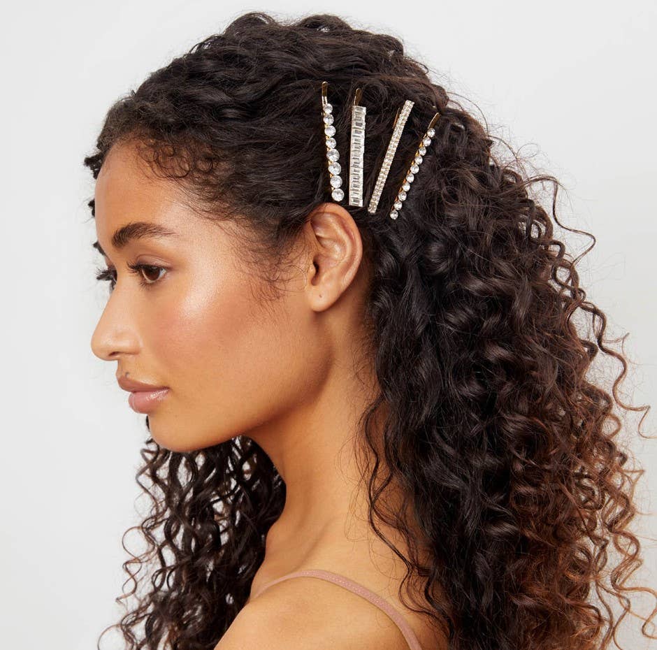 Woman with curly hair wearing decorative hair pins against a neutral background
