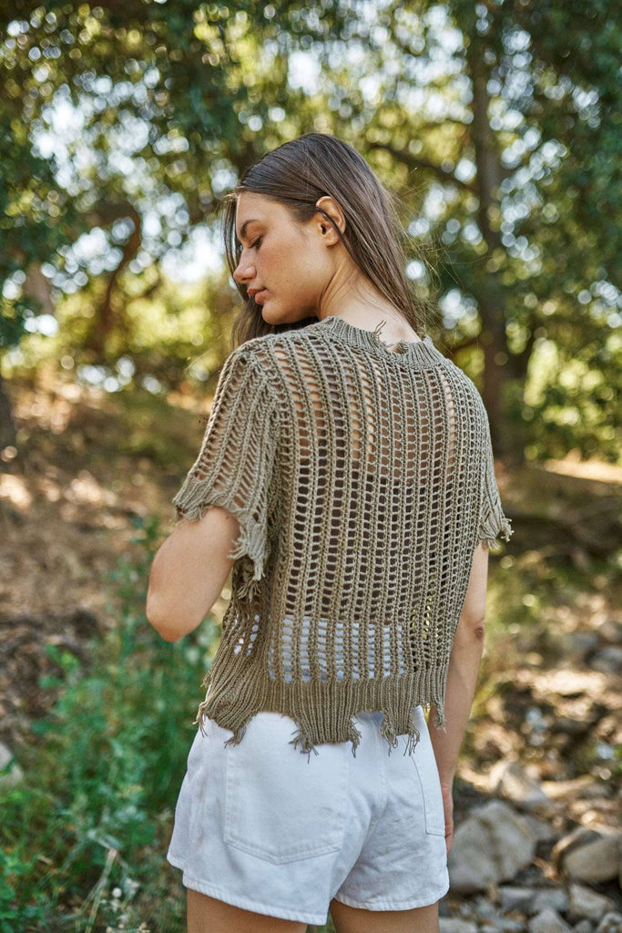 Woman wearing a crochet top and white shorts in a natural setting