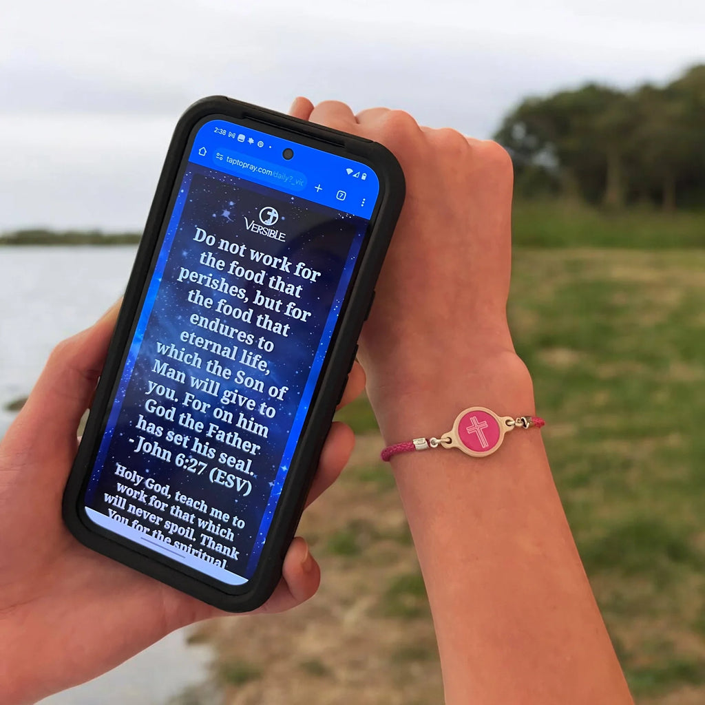Person holding a phone with a verse displayed outdoors