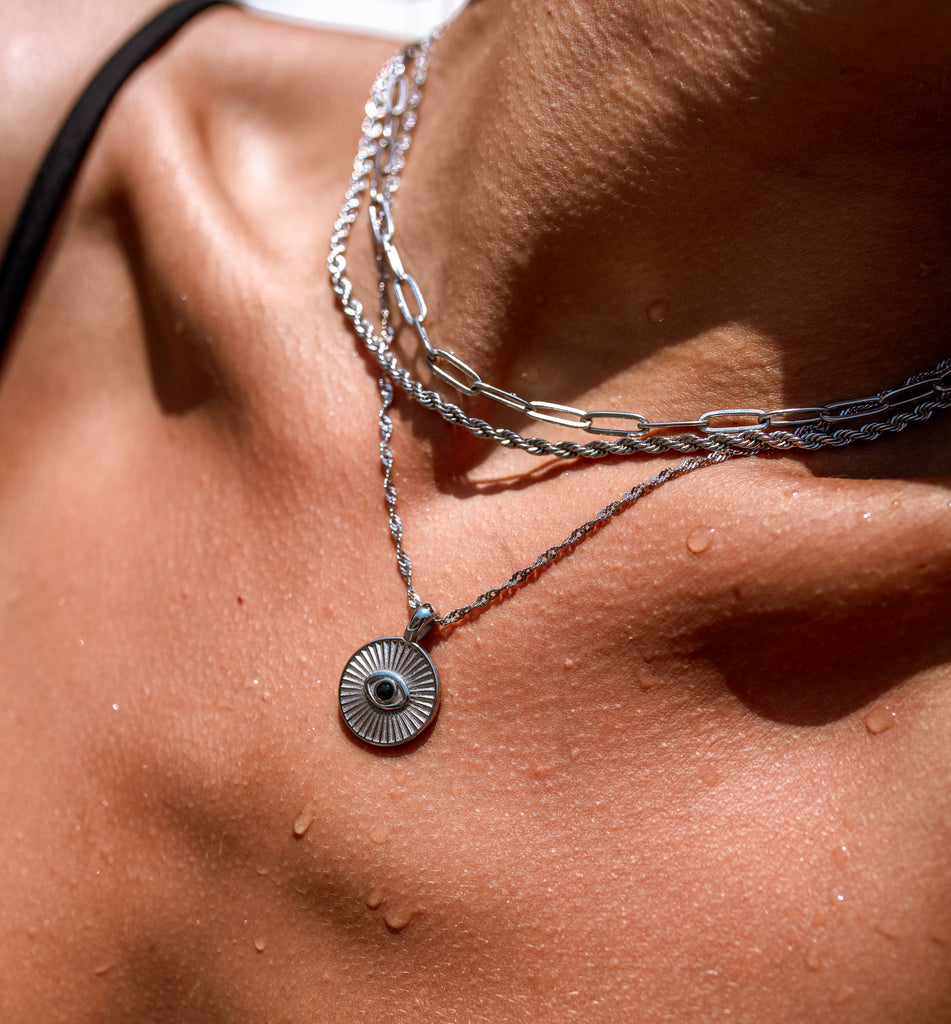 Close-up of a necklace with a circular pendant on a person's neck.